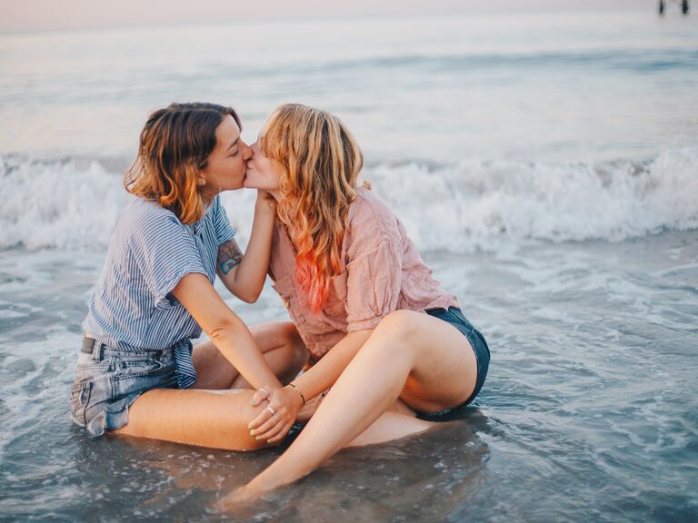 Couple share a kiss while sitting in the surf. 