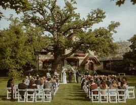 Couple exchanging their vows underneath a large tree outside the charming venue