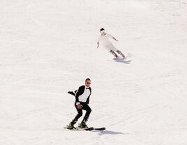 bride and groom skiing down the mountain in their wedding attire