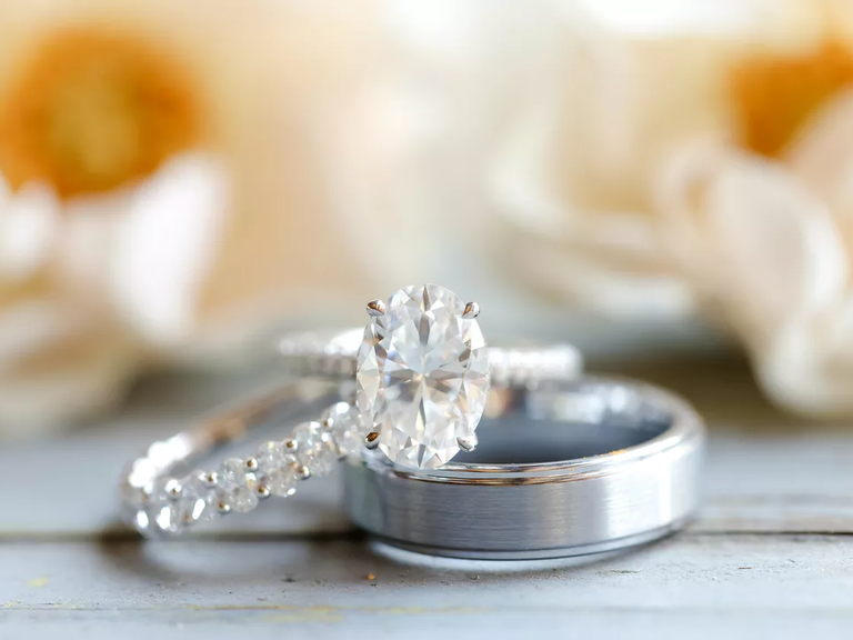 A silver engagement ring sits atop a silver wedding band.