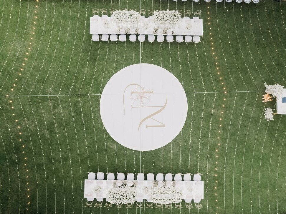 An aerial shot of the geometric pattern of the lights against the green grass at this wedding reception.