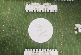 An aerial shot of the geometric pattern of the lights against the green grass at this wedding reception.