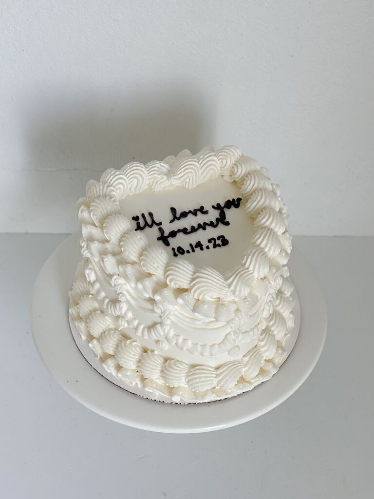 one tier heart shaped wedding cake with i'll love you forever written in black icing on top