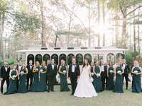 Couple with their wedding party in front of a vinatge white trolley