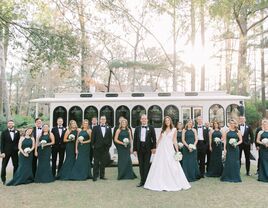 Couple with their wedding party in front of a vinatge white trolley