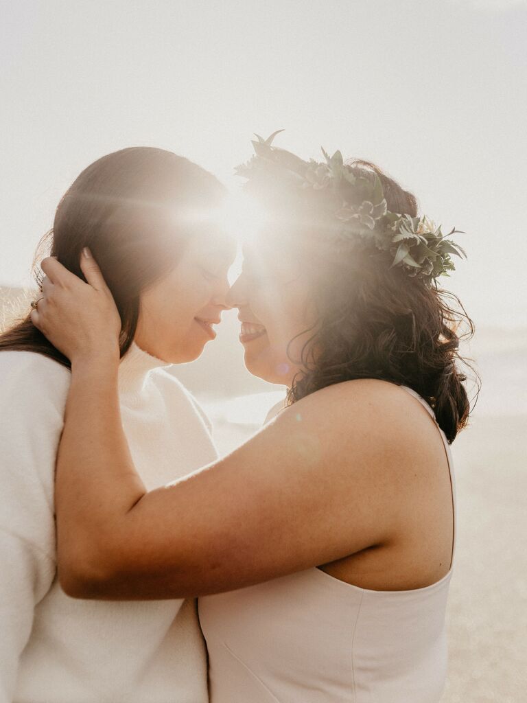 Couple embraces while the sun shines in the background. 
