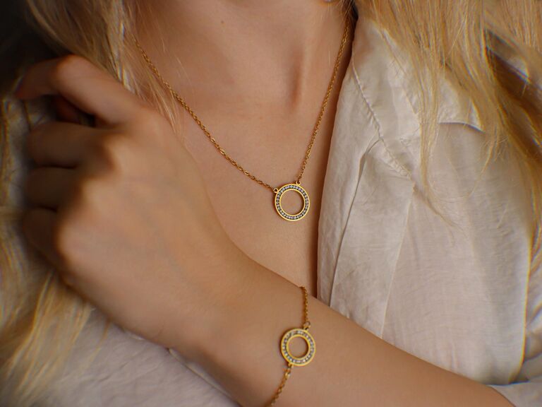 A gold circle pendant necklace with small crystals and matching chain bracelet from Etsy