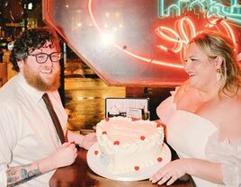 The happy couple smile for the camera while holding their wedding cake.