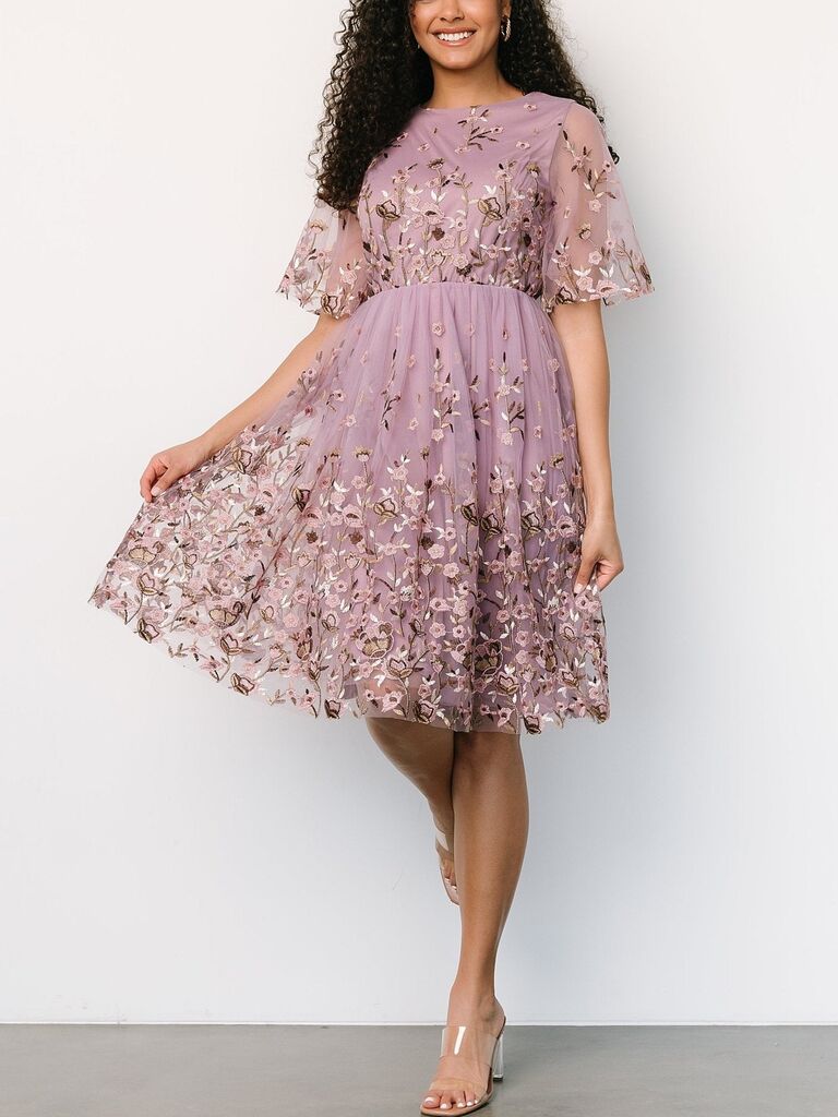 Model wearing pastel purple floral embroidered wedding guest dress