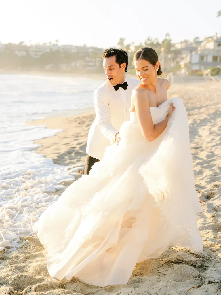 Wave Getting Bride and Groom Wet on Sandy Beach