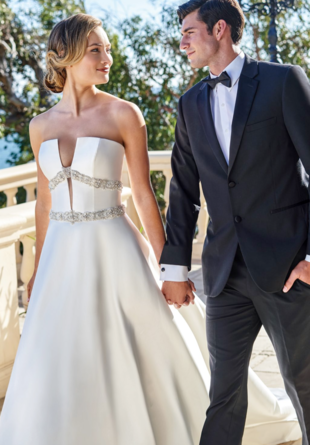 bride in strapless dress with plunging neckline holding hands with groom in gray tuxedo