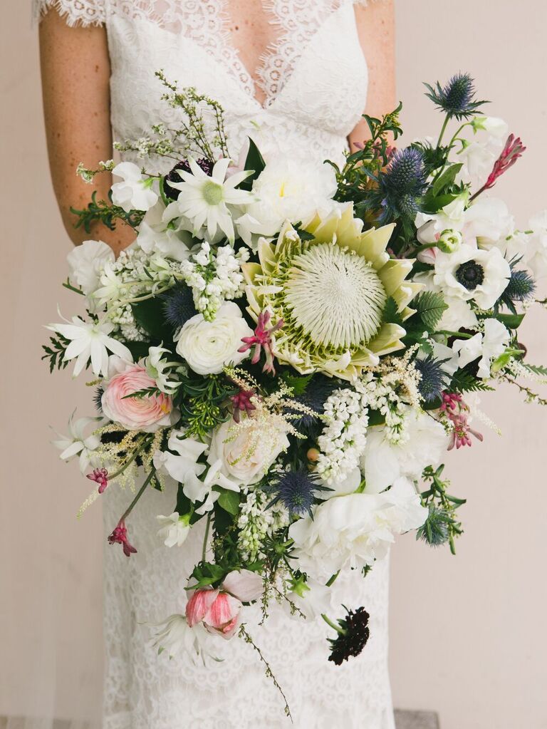 Bride holding bouquet with thistle, rose, and kind protea.