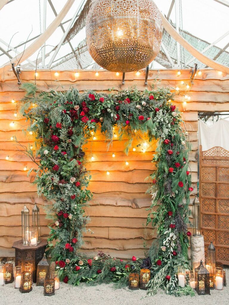 Christmas-inspired arch made of evergreen leaves and red roses