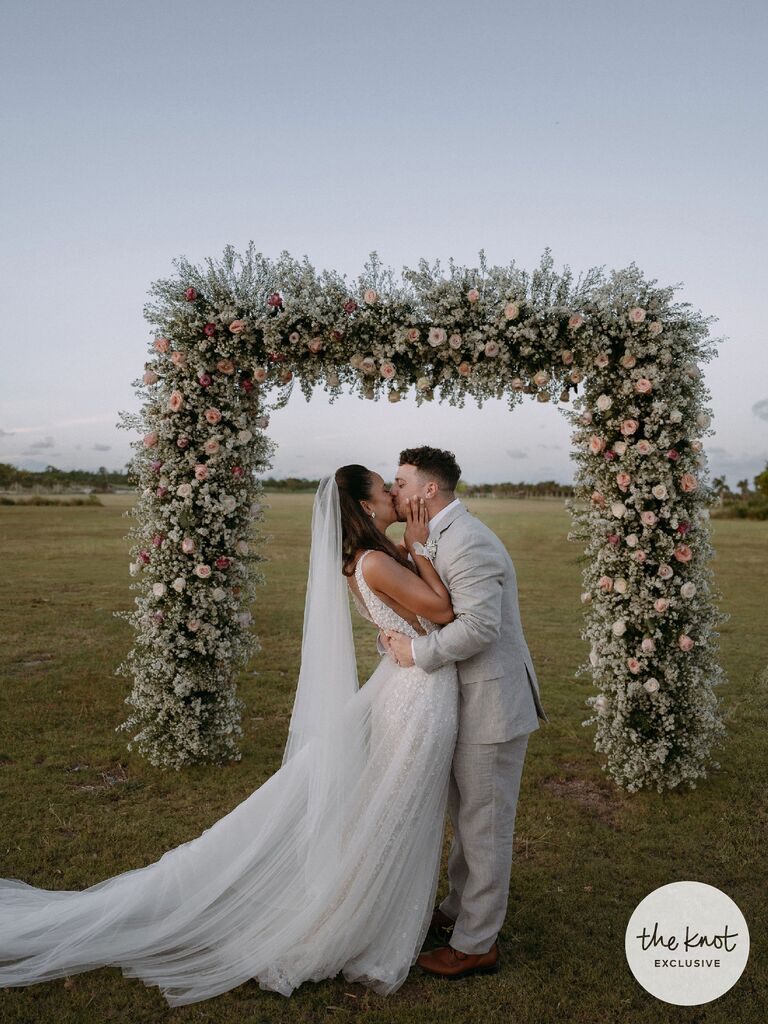 Erika Priscilla and Scott kissing under flower ceremony arch