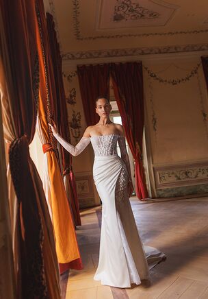 Cliff dress is a sophisticated mermaid silhouette with an off-the-shoulder neckline, designed to highlight the bride's elegance and confidence. Crafted from delicate Chantilly lace, the gown is richly embellished with dimensional 3D appliqués that create a romantic and artistic texture. The lace placement on the corset is intentionally asymmetrical, adding a modern twist to the timeless design. The corset fastens with a hidden zipper at the back for a clean finish. An additional overskirt made of smooth satin can be added for extra volume and drama, perfect for a grand entrance or ceremony moment. The long fitted sleeves are closed with subtle zippers and are non-detachable, offering a graceful and elongated silhouette. Available for order in two shades: ivory and light ivory.