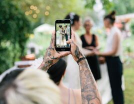 Wedding guest taking photo of couple during ceremony