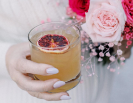 Bride holding orange wedding mocktail with bouquet