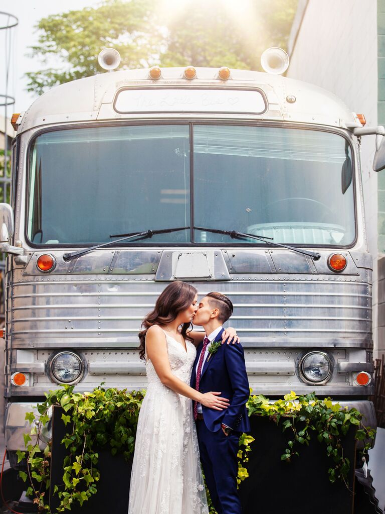 Couple standing in front of wedding bus