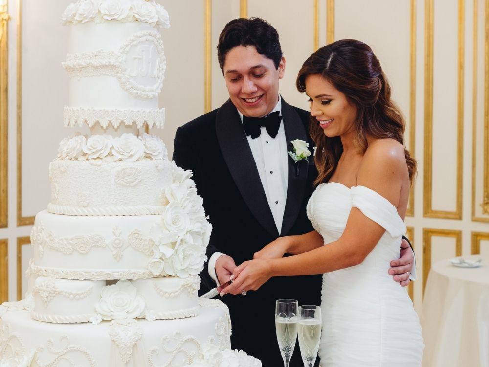 couple cutting dramatic white wedding cake