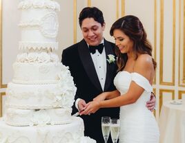 couple cutting dramatic white wedding cake