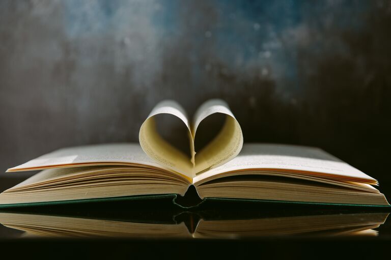 An open book with the pages folded into a heart shape