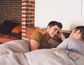 two men lying in bed and talking