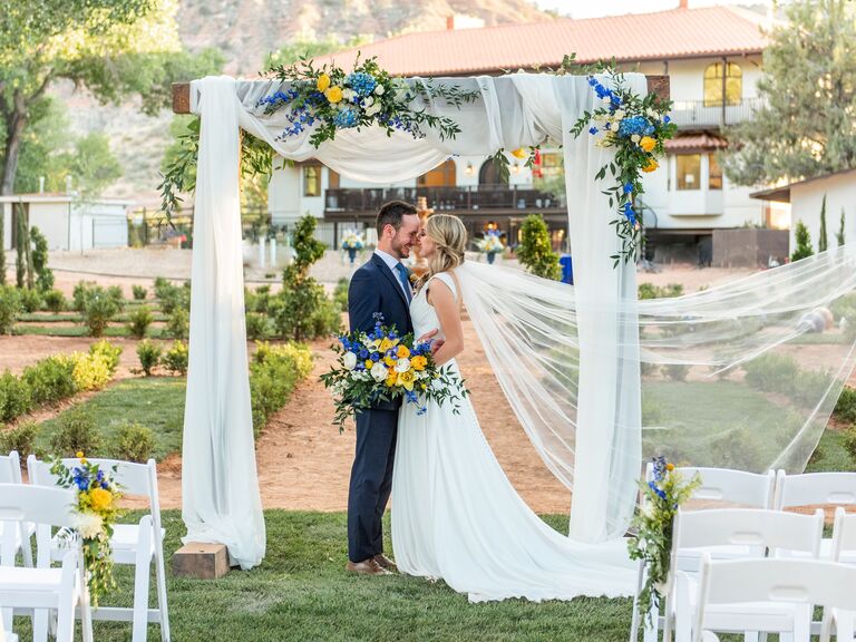 Happy couple underneath the ceremony arch outside in the property's garden