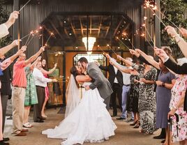 Couple kissing while guests celebrate with sparklers