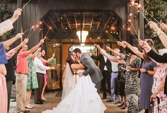 Couple kissing while guests celebrate with sparklers