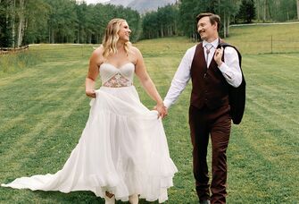 Bride and groom holding hands in field