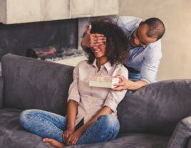 Man covering woman's eyes and surprising her with gift