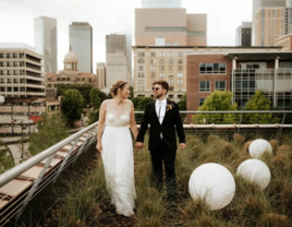 Bride and Groom Take a Stroll Through the Grass at Sunset Coffee Building wedding venue in Houston, Texas