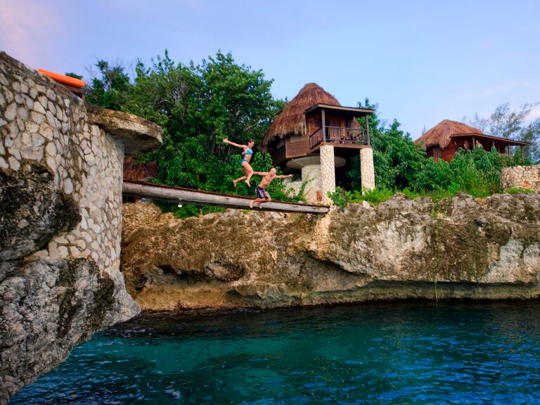 Couple jumping from bridge into water of Jamaica.