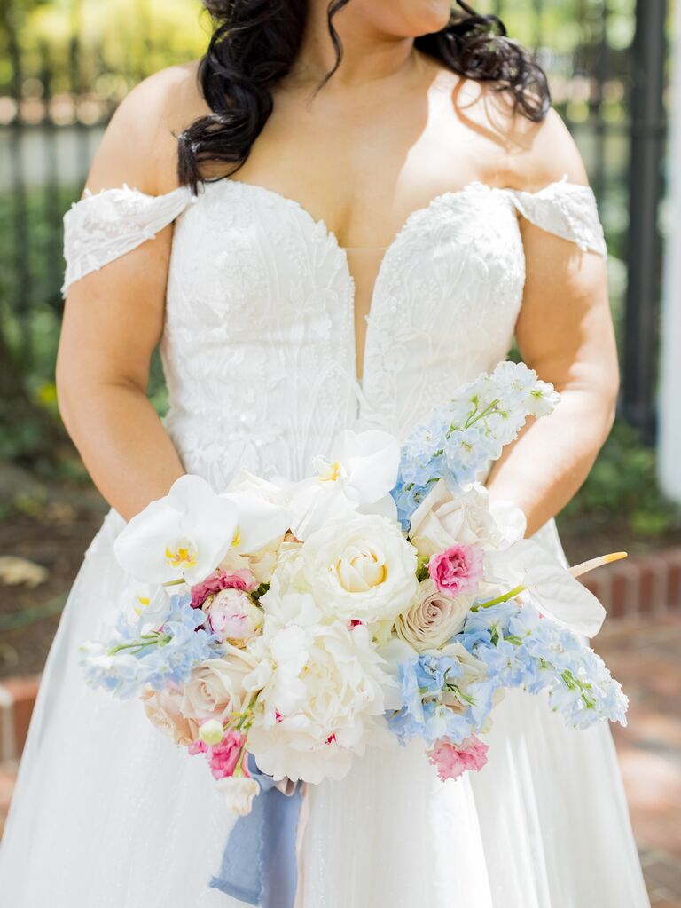A bride holds a stunning springtime bouquet of pale blues, creams and pinks.