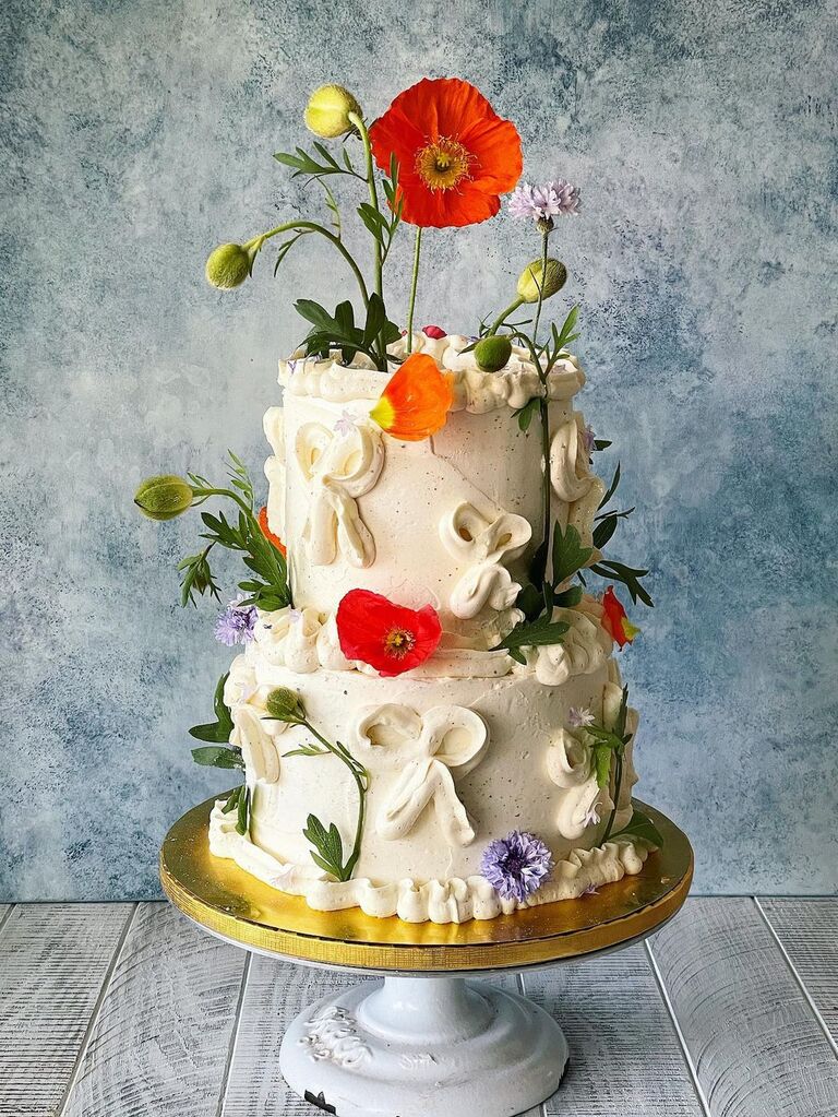 A white wedding cake covered in wildflowers