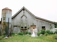 Bride and groom stand in front of a barn on their wedding day