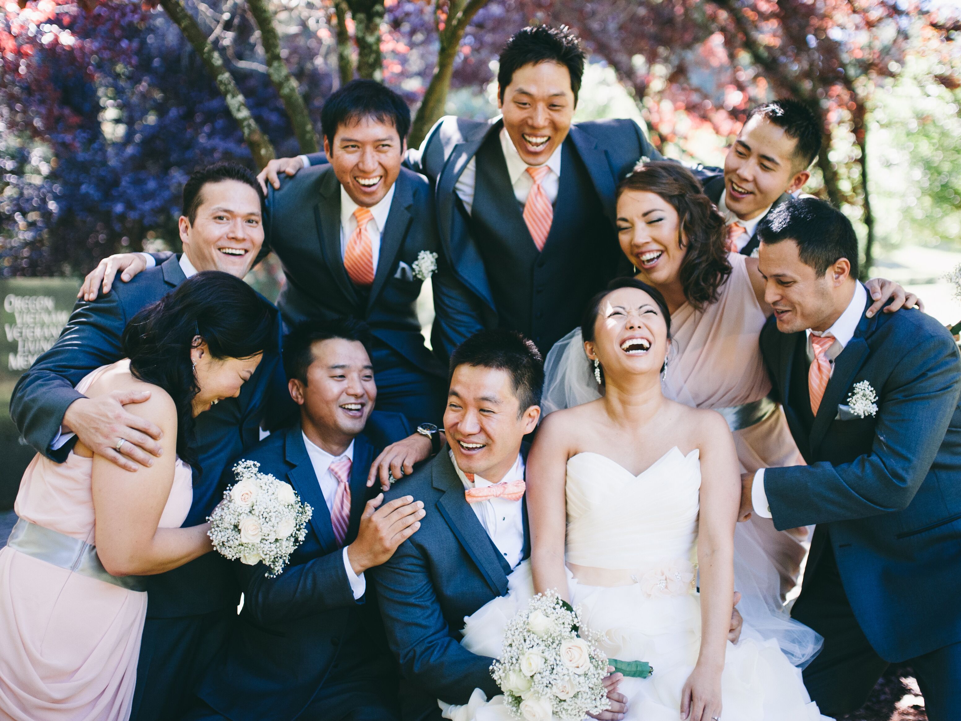Mismatched wedding party with more groomsmen than bridesmaids laughing together with the bride and groom.