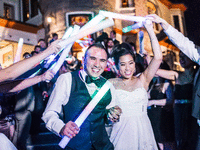 Bride and groom surrounded by their guests holding glow sticks.
