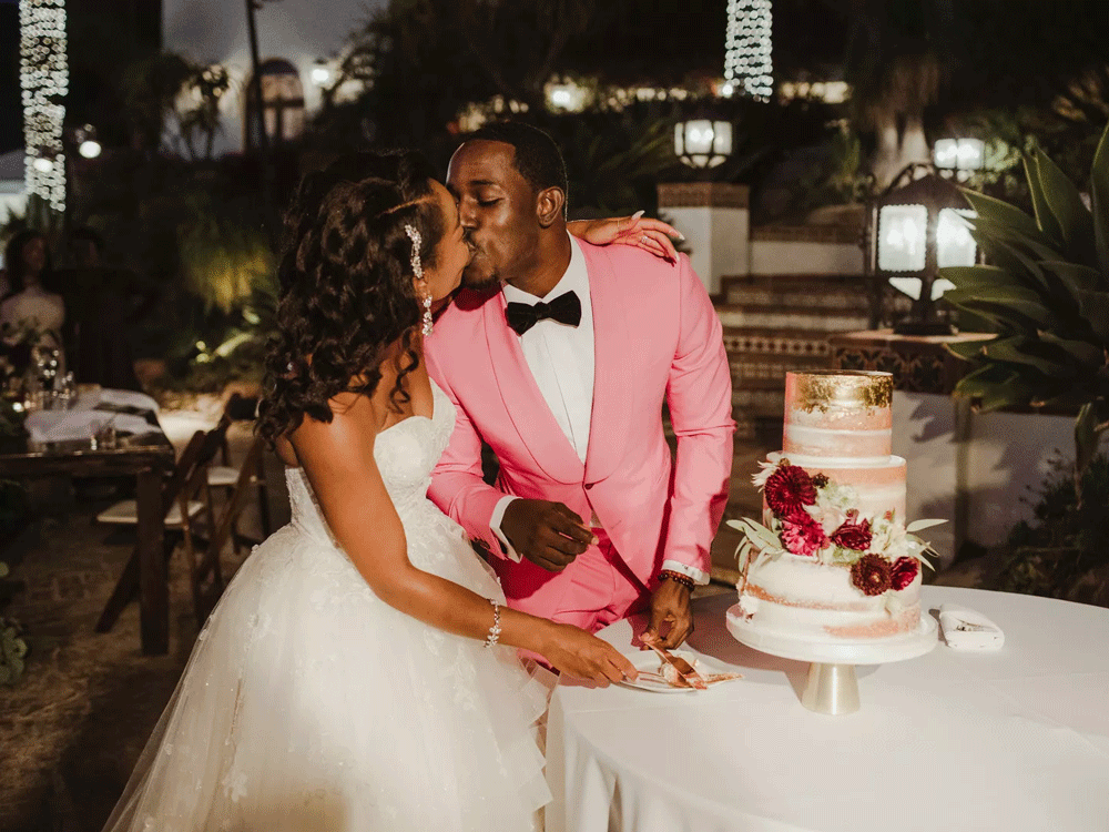 Bride and groom kissing while cutting their wedding cake. 
