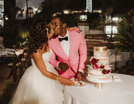 Bride and groom kissing while cutting their wedding cake. 