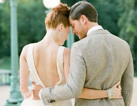 Outdoor wedding beneath an old tree with orange bridesmaid dresses and charcoal groomman suits.