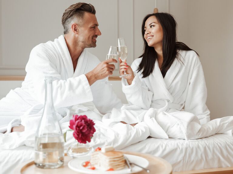 Couple drinking champagne in hotel bed