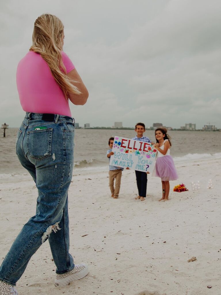 Kids holding up sign at proposal on beach