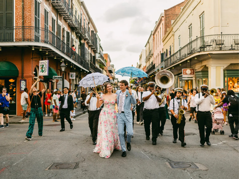 Newlyweds holding hands during second line celebration