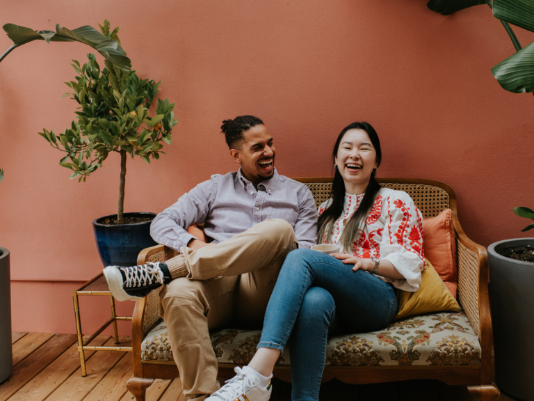 Couple smiling and laugjing with each other on couch