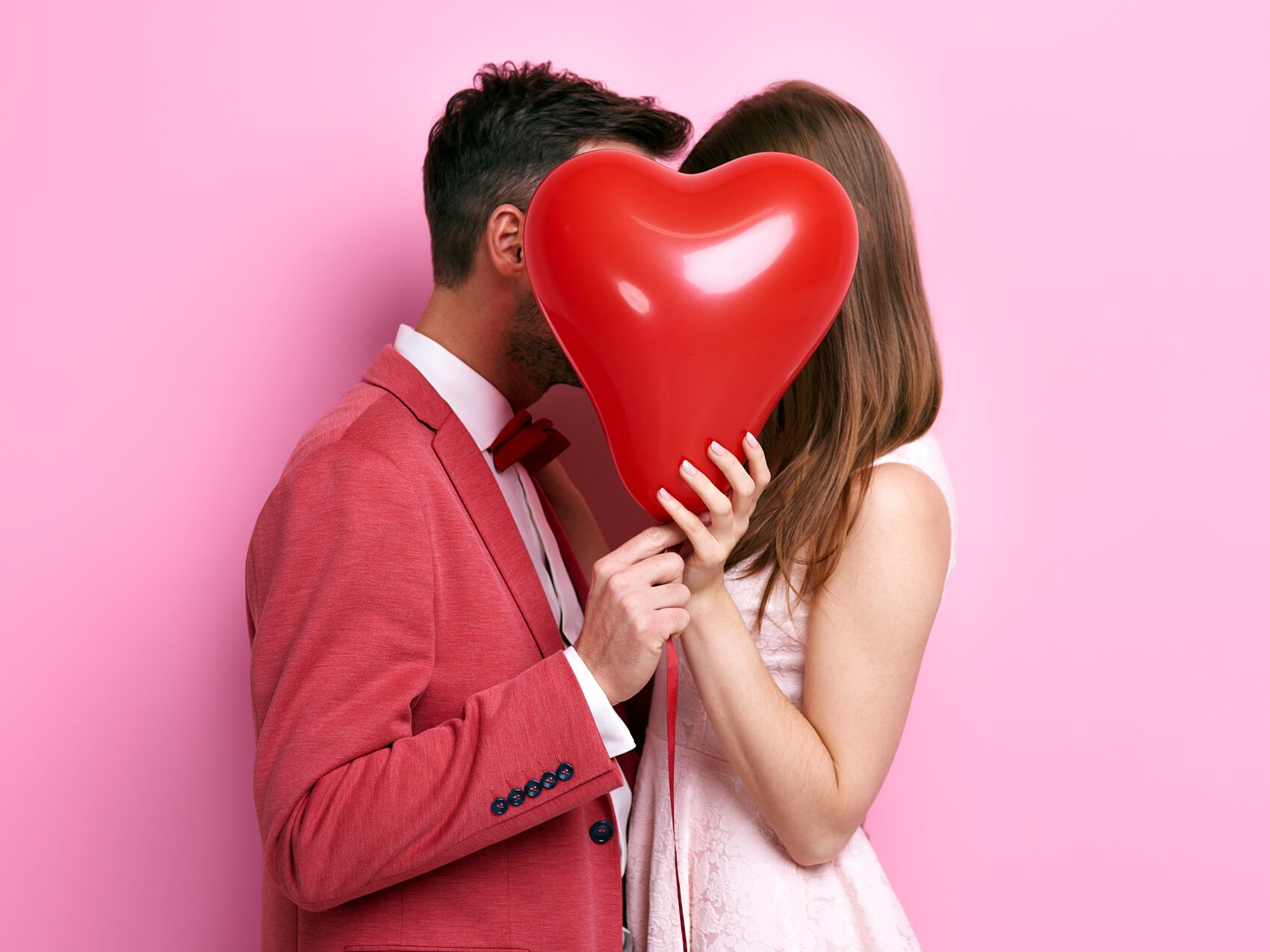 man and woman holding Valentine's Day heart-shaped balloon