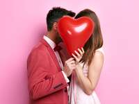man and woman holding Valentine's Day heart-shaped balloon
