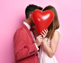 man and woman holding Valentine's Day heart-shaped balloon