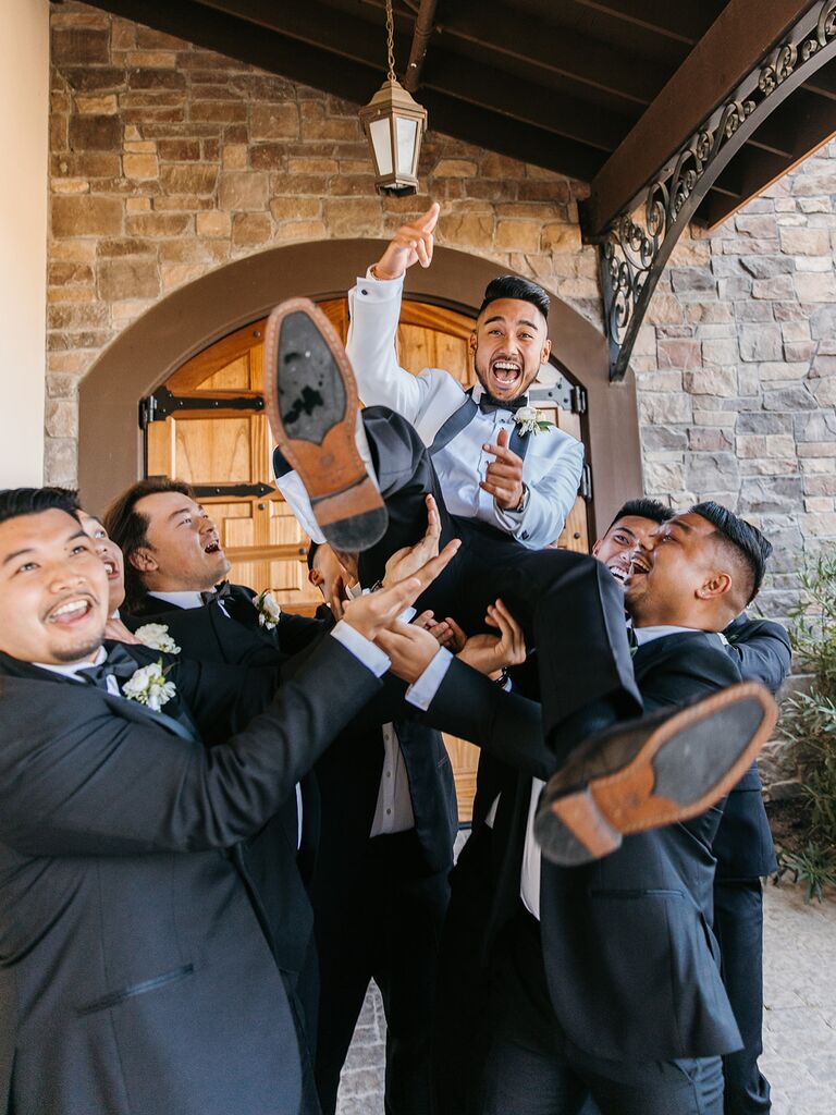Groomsmen holding up groom for fun wedding photo