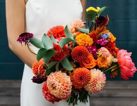Bridal bouquet featuring beautiful dahlias in shades of red, orange, and pink. 